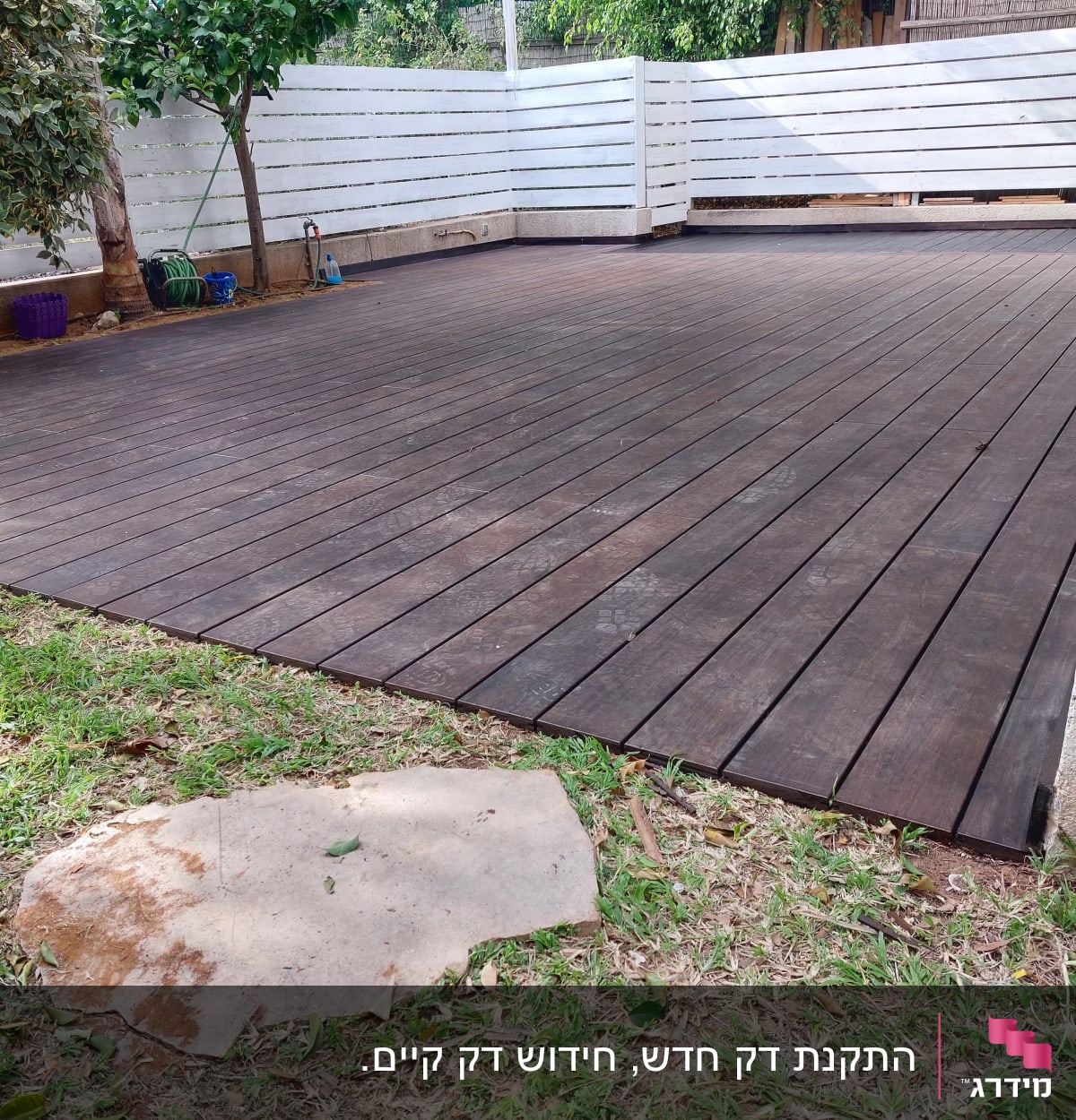 דק עץ חום בגינה עם גדר לבנה